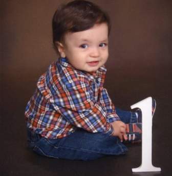 Smiling baby in plaid sitting by the number 1